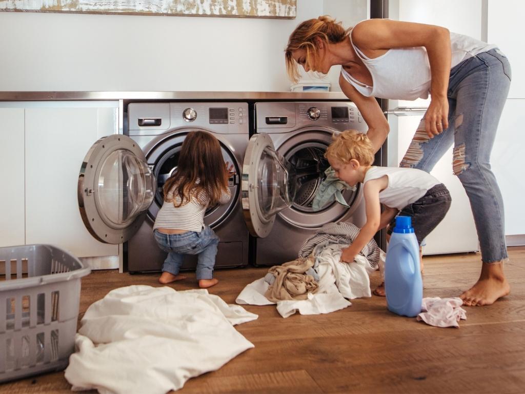 mom and toddlers removing clean laundry from dryer